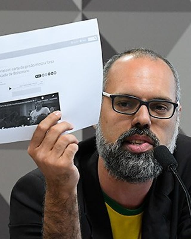 Foto de Allan dos Santos — Jornalista Allan dos Santos mostrando um papel numa reunião da Comissão Parlamentar Mista de Inquérito de Fake News.